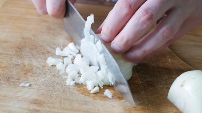 Девушка режет лук кубиками Девушка режет лук кубиками