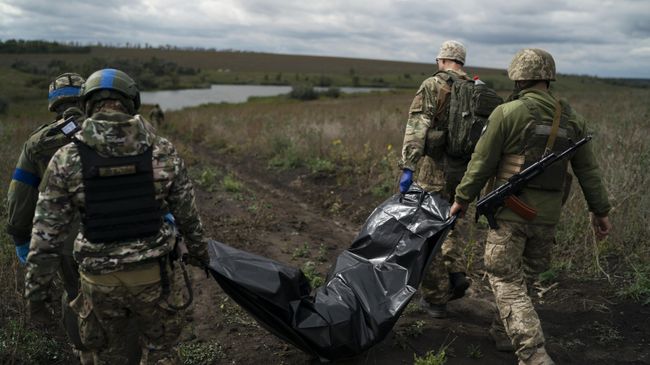 Украинские военнослужащие несут тело погибшего военного