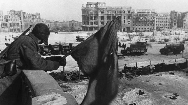 Боец держит флаг над освобожденным Сталинградом Боец держит флаг над освобожденным Сталинградом