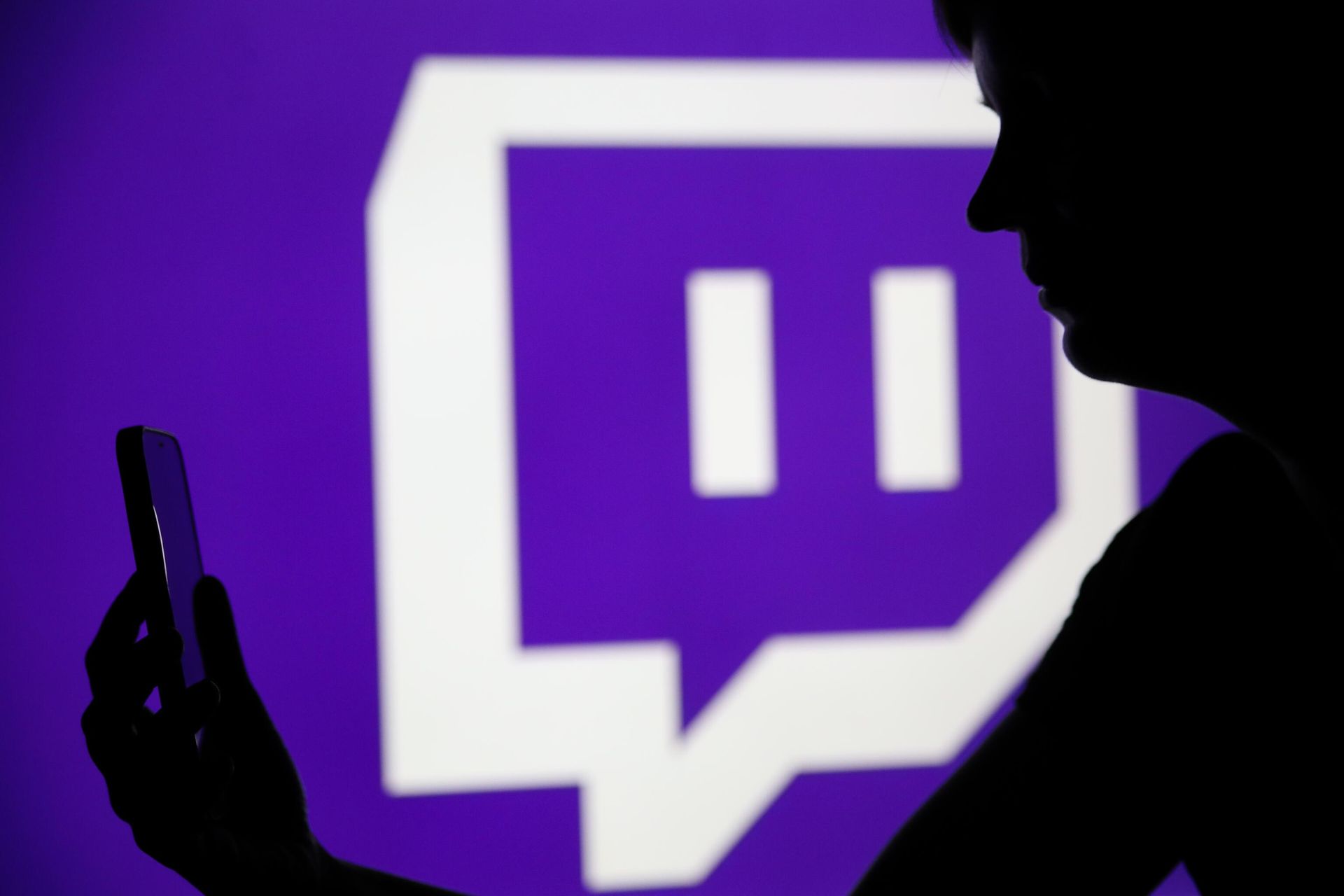 Мужчина со смартфоном на фоне логотипа платформы Twitch - РИА Новости, 1920, 28.02.2025