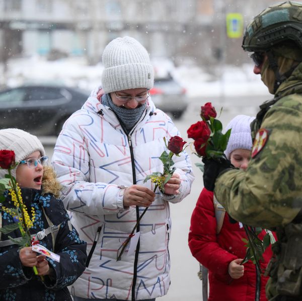 Курсант Новосибирского военного ордена Жукова института им. генерала армии И. К. Яковлева войск национальной гвардии РФ поздравляет женщину с детьми с Международным женским днем на улице Кирова в Новосибирске