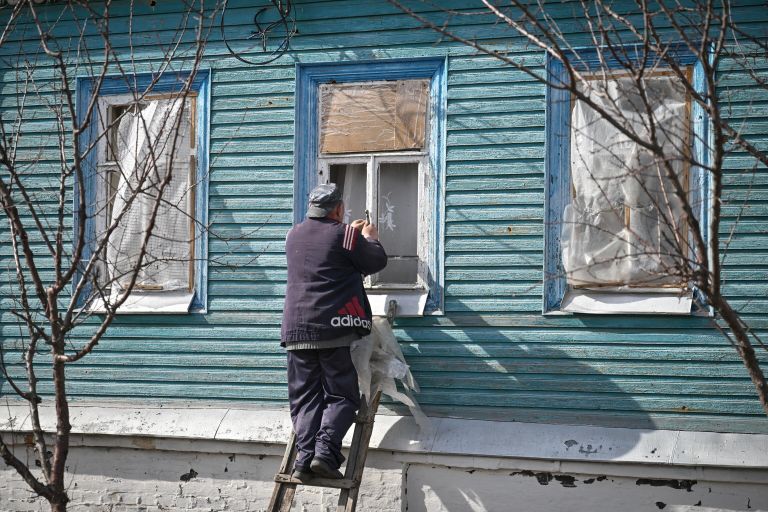 Мужчина заколачивает окна в своем доме в освобожденной Судже Мужчина заколачивает окна в своем доме в освобожденной Судже