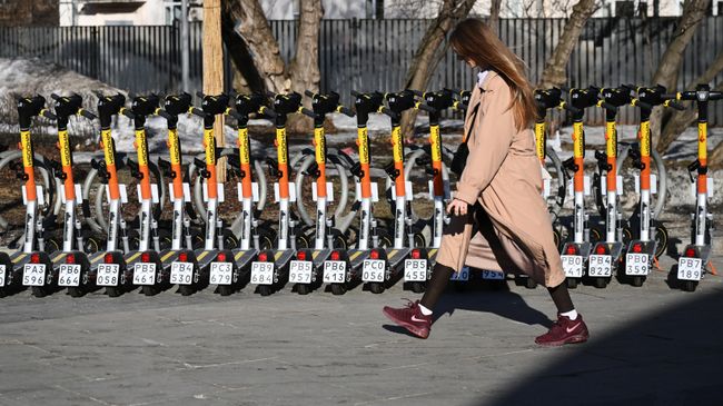 Девушка у пункта электросамокатов на одной из улиц в Москве