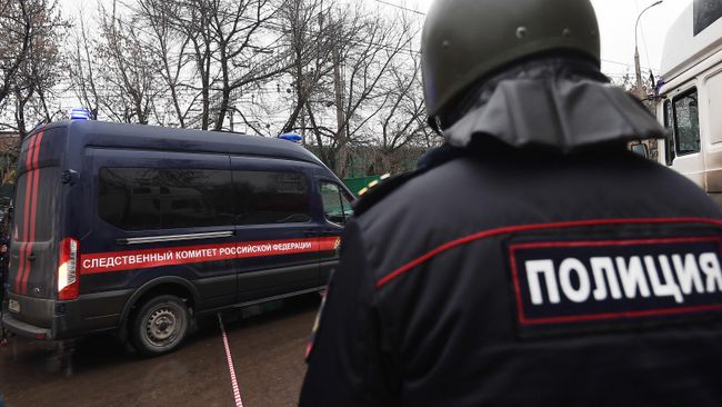 Сотрудник полиции рядом с автомобилем Следственного комитета России