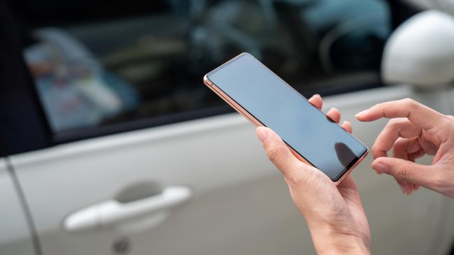 Девушка использует смартфон, чтобы открыть двери автомобиля
