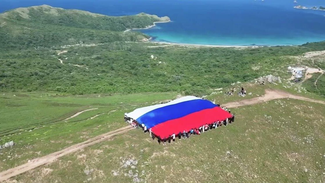 На полуострове Гамова в Приморье развернули огромный флаг России На полуострове Гамова в Приморье развернули огромный флаг России - РИА Новости, 1920, 12.06.2025