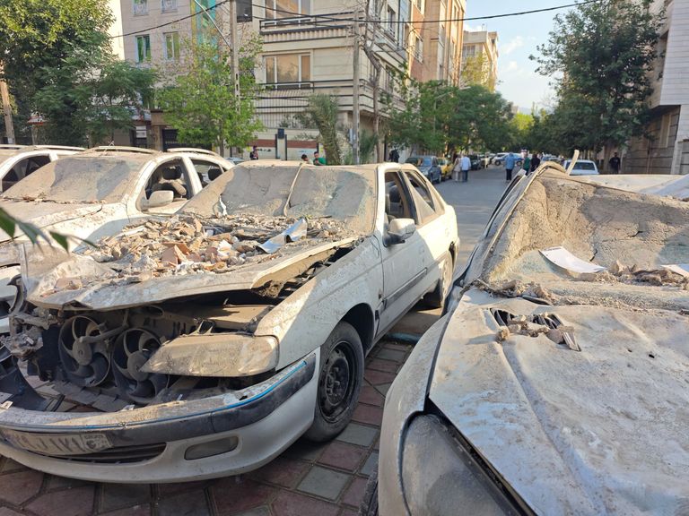 Поврежденные автомобили на площади в районе Нармак в Тегеране после израильских авиаударов