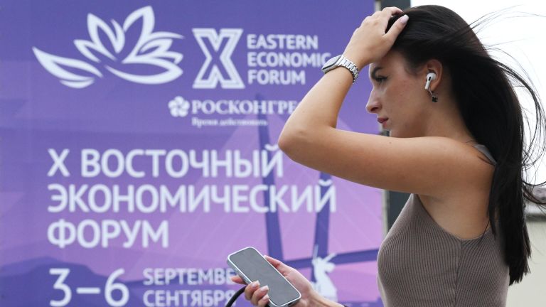 Девушка на фоне баннера Восточного экономического форума на улице Светланская во Владивостоке Девушка на фоне баннера Восточного экономического форума на улице Светланская во Владивостоке
