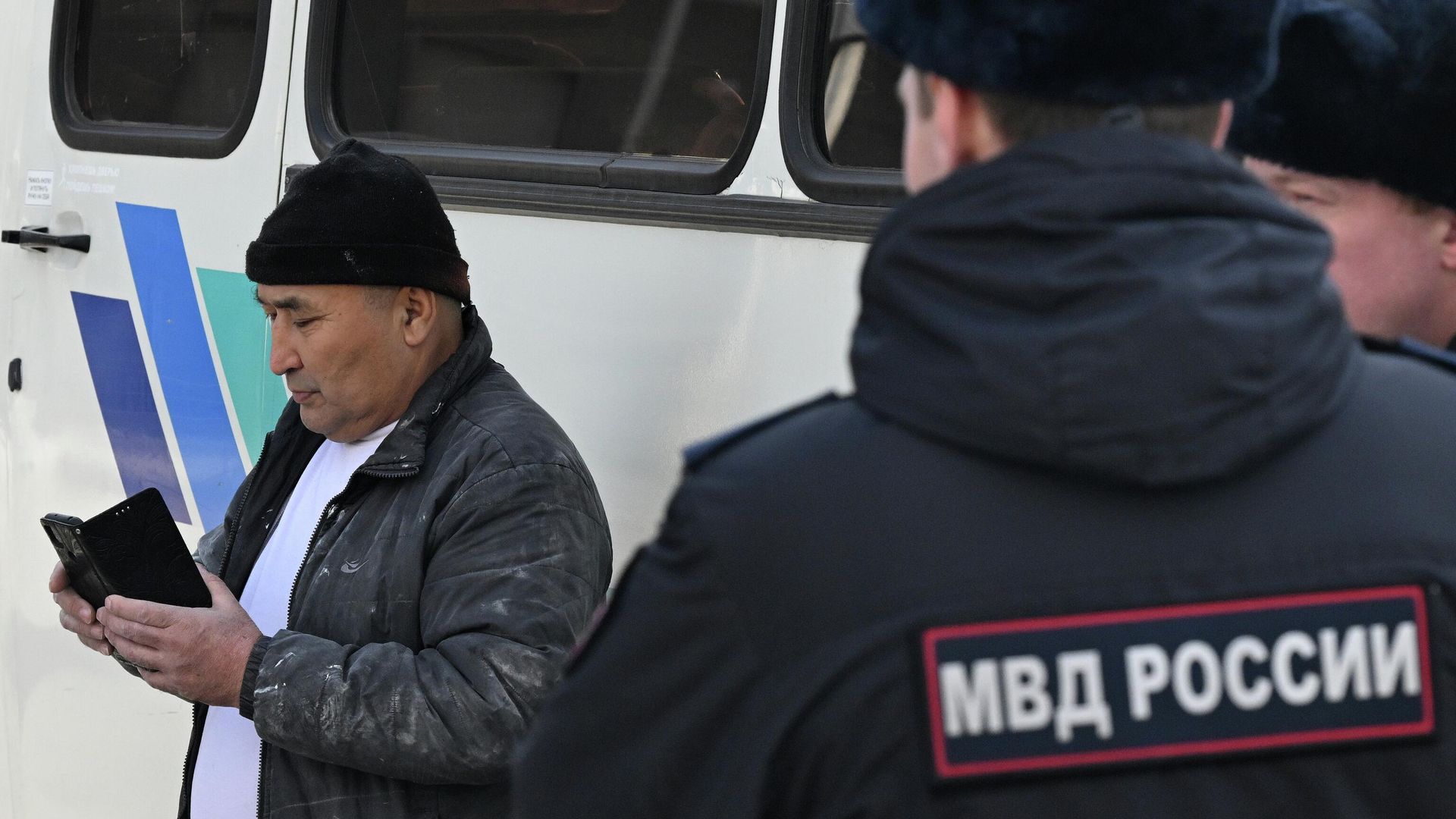 Задержанный иностранный трудовой мигрант возле автобуса полиции - РИА Новости, 1920, 24.01.2026