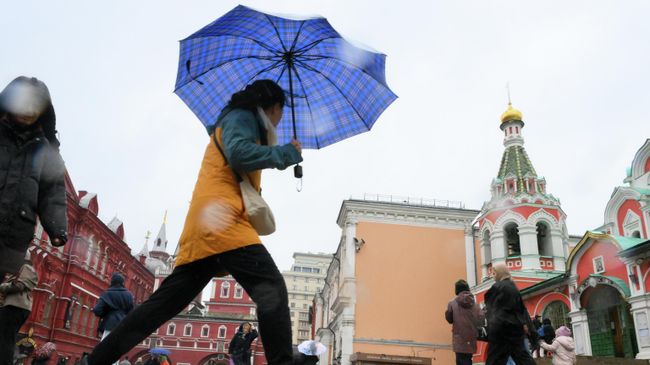 Прохожие идут под дождем по улице в Москве