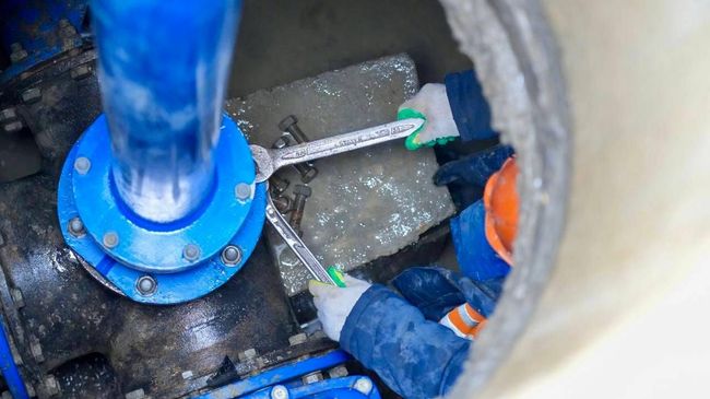 Работник ремонтирует сеть водоснабжения