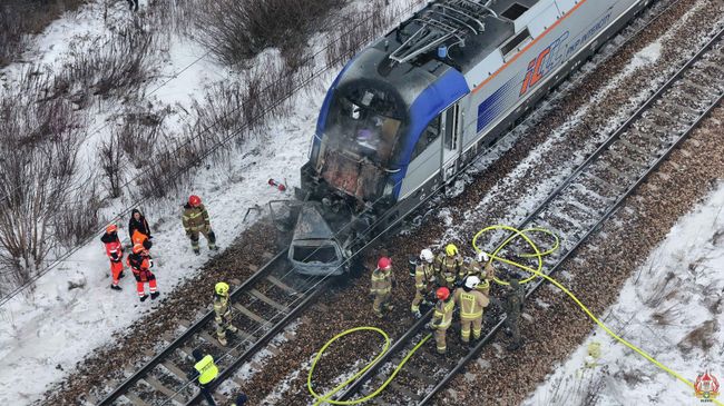 Пожарные на месте столкновения двух поездов с автомобилем под Варшавой