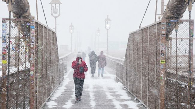 Прохожие во время снегопада на Бруклинском мосту в Нью-Йорке