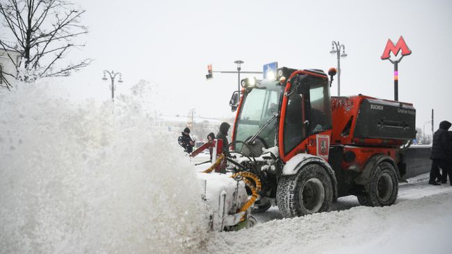 Расчистка тротуара во время снегопада в Москве