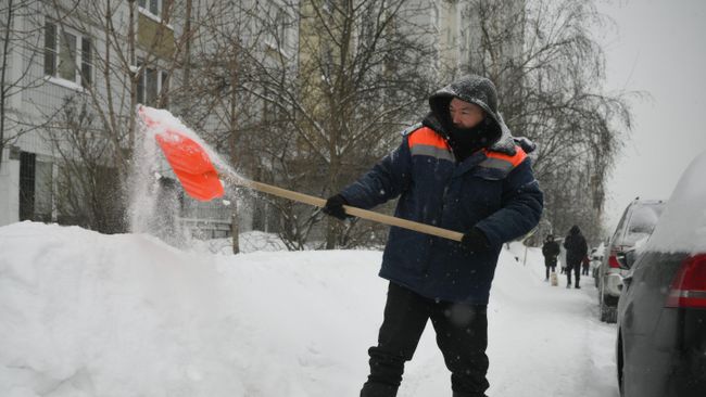 Сотрудник коммунальных служб очищает тротуар от снега в Москве