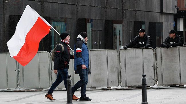 Мужчина с флагом Польши в Варшаве