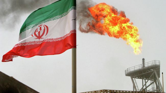 Иранский флаг и факел газовой горелки на нефтедобывающей платформе