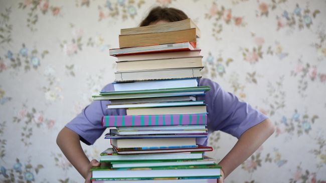 Девочка держит стопку книг 