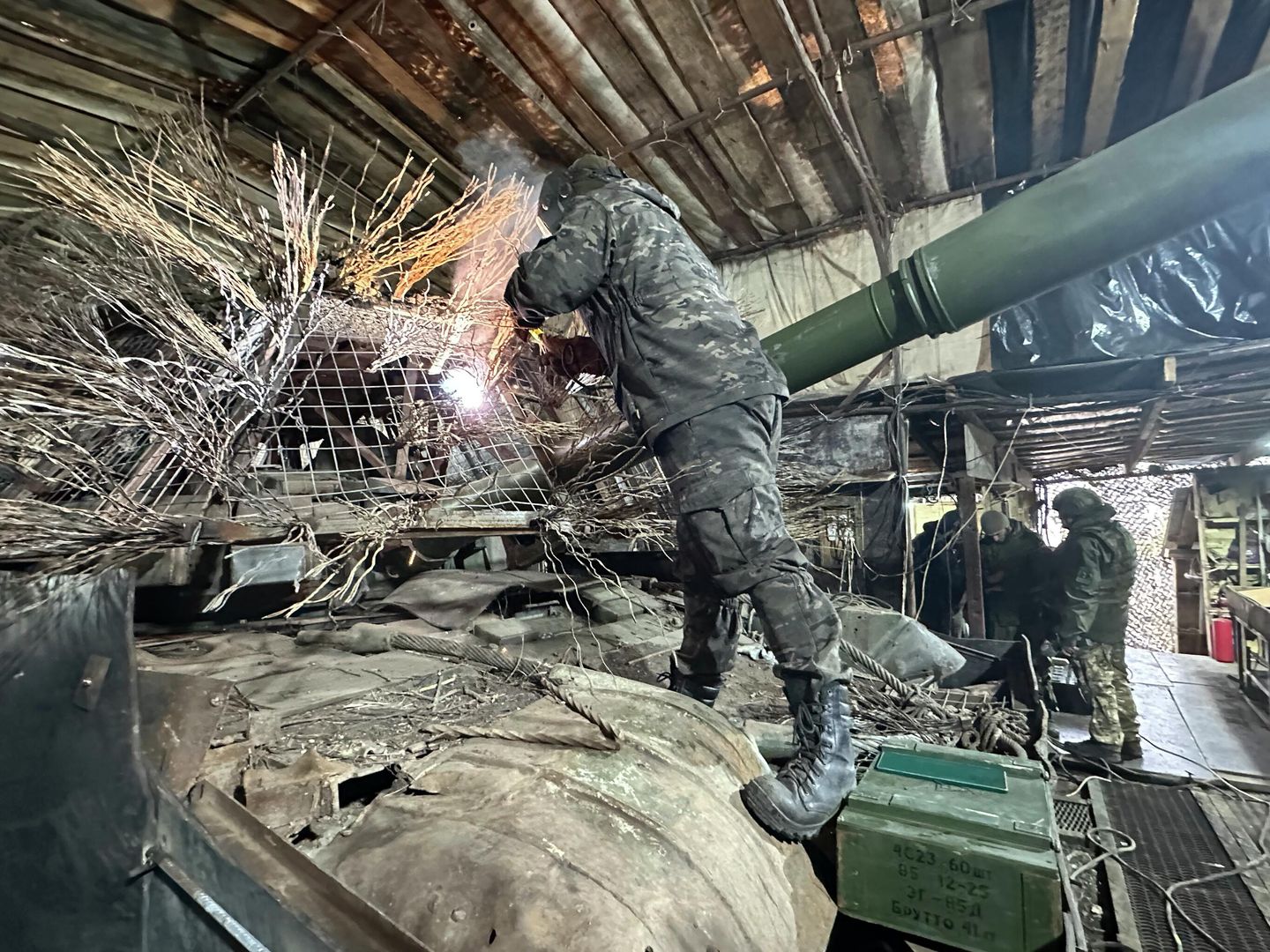 Боец танкового батальона наваривает на башню дополнительную защиту от дронов Боец танкового батальона наваривает на башню дополнительную защиту от дронов