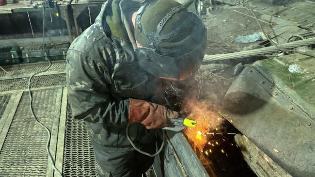 Боец танкового батальона наваривает дополнительную защиту на нижнюю лобовую деталь брони корпуса танка Боец танкового батальона наваривает дополнительную защиту на нижнюю лобовую деталь брони корпуса танка