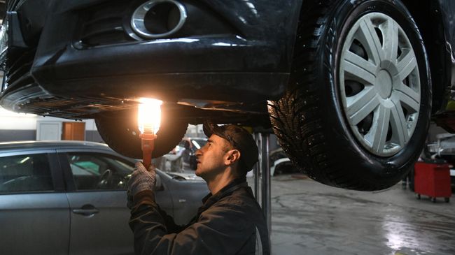 Автомеханик осматривает автомобиль