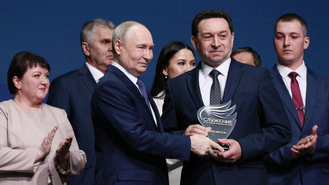 Президент РФ Владимир Путин вручает приз в номинации Мужество и героизм - на благо служения Родине директору Серпейской средней школы, депутату Думы Мещовского муниципального округа Калужской области Евгению Филонову на церемонии награждения победителей III Всероссийской муниципальной премии Служение. 21 апреля 2026