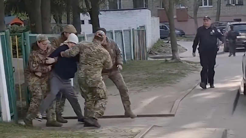 Сотрудники ТЦК насильно мобилизуют мужчину с территории детского сада. Кадр видео - РИА Новости, 1920, 26.06.2026