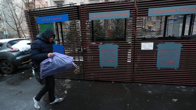Мужчина несет мусор к контейнерам для раздельного сбора отходов в одном из дворов в Москве
