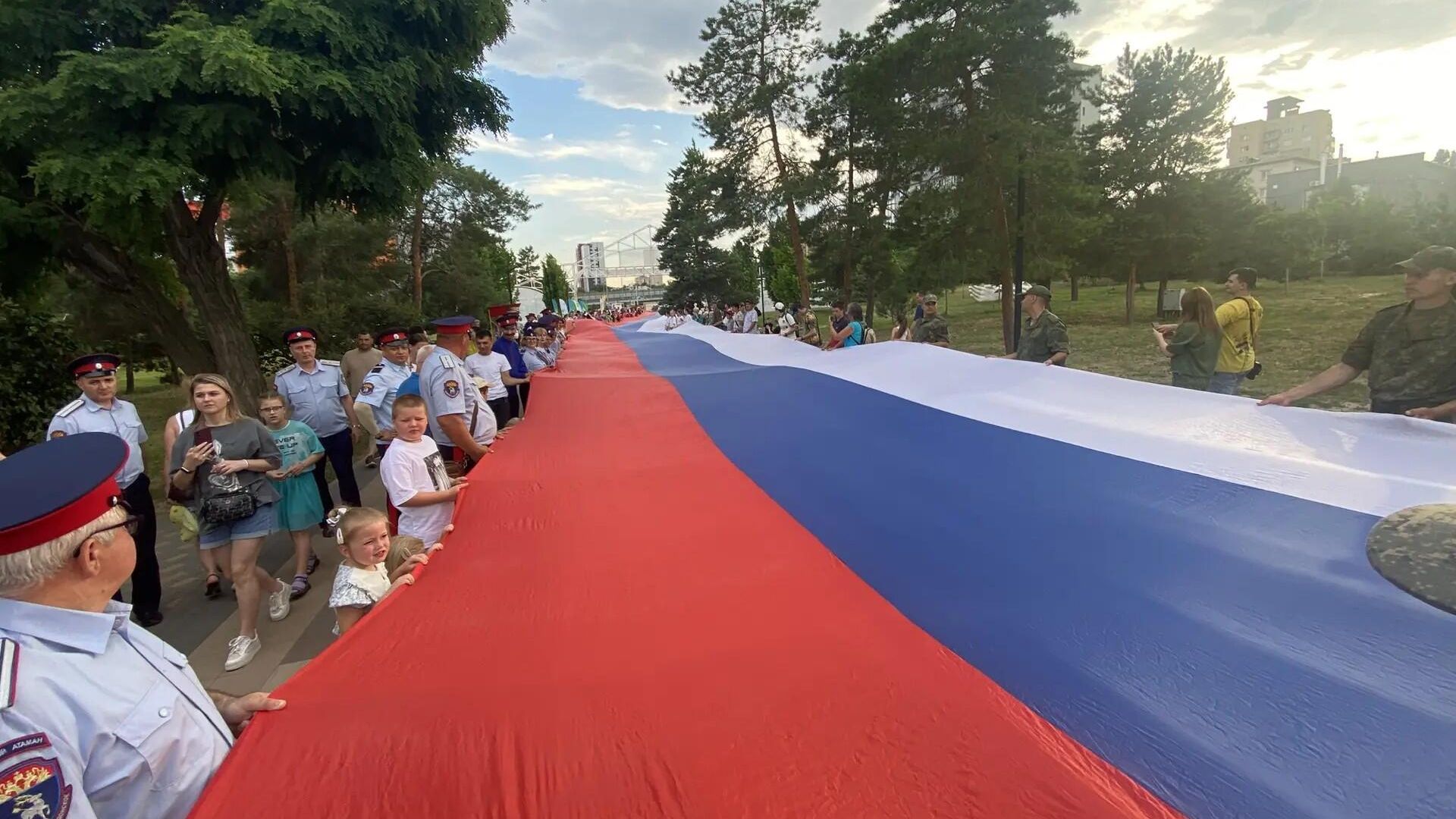 Стометровый триколор пронесли волгоградцы в народных костюмах по аллее парка в День России Стометровый триколор пронесли волгоградцы в народных костюмах по аллее парка в День России - РИА Новости, 1920, 12.06.2026