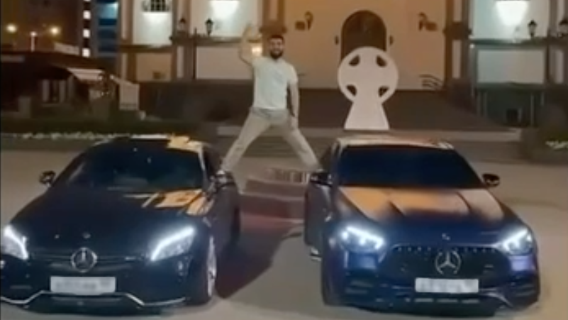 Кадр видео с мужчиной, вставшим в шпагате между автомобилями на фоне собора Александра Невского - РИА Новости, 1920, 15.07.2026