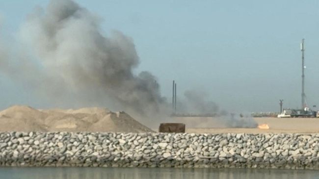 Дым поднимается в иракском порту Фау после падения беспилотника. Кадр видео