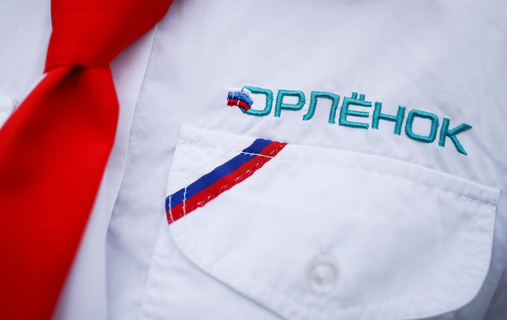 Вышивка с названием Всероссийского детского центра Орлёнок на форменной одежде вожатого на торжественной линейке Вышивка с названием Всероссийского детского центра Орлёнок на форменной одежде вожатого на торжественной линейке - РИА Новости, 1920, 22.07.2026