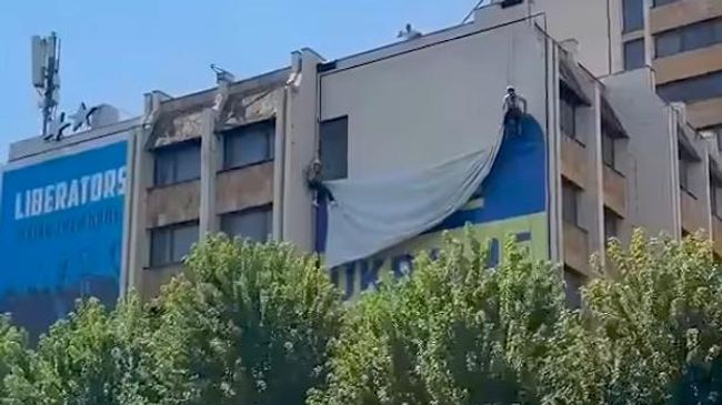 Рабочие снимают флаг Украины со здания в Приштине