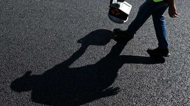 Рабочий измеряет параметры асфальта