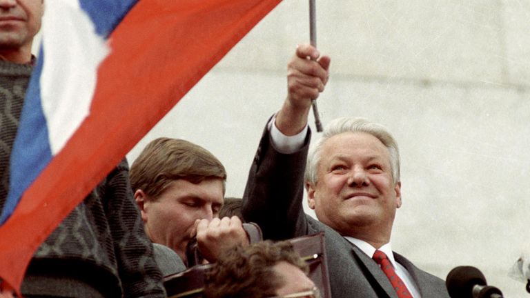Президент России Борис Николаевич Ельцин стоит на трибуне с флагом в руках на митинге перед зданием Верховного Совета РСФСР