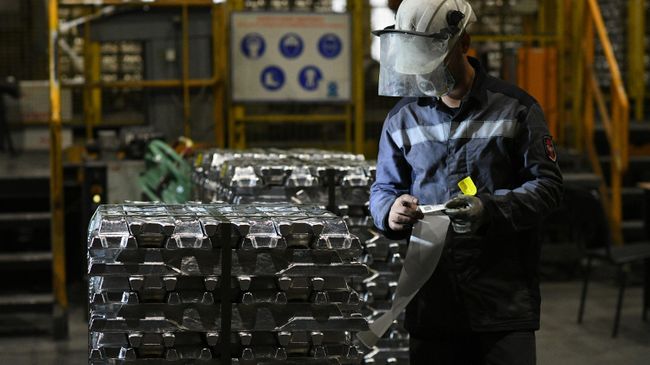 Сотрудник маркирует алюминиевые слитки в литейном цехе 