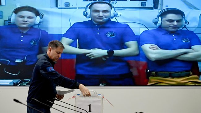 Доверенное лицо экипажа МКС Андрей Бабкин опускает бюллетени в урну на выборах депутатов Госдумы РФ 