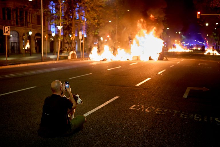 Мужчина фотографирует горящие баррикады во время столкновений с полицией Мужчина фотографирует горящие баррикады во время столкновений с полицией