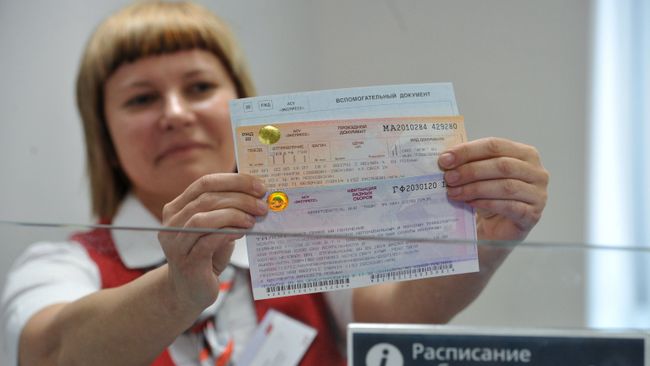 Билетный кассир держит в руках проездные документы в Крым Билетный кассир держит в руках проездные документы в Крым