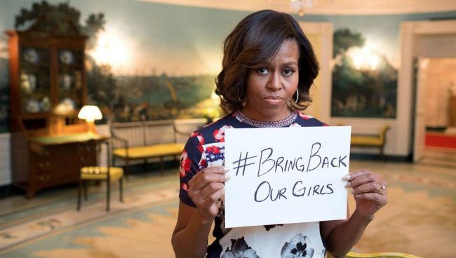 Мишель Обама держит белый лист бумаги, на котором написан хэштег # BringBackOurGirls Мишель Обама держит белый лист бумаги, на котором написан хэштег # BringBackOurGirls