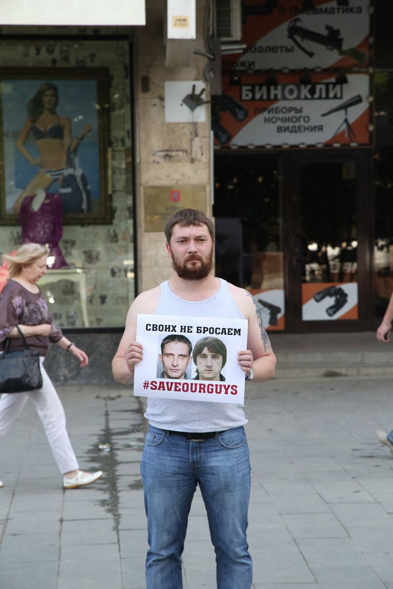 Мужчина держит плакат с фото задержанных на Украине журналистов телеканала Лайф Ньюз Олега Сидякина и Марата Сайченко