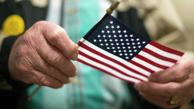 Американский ветеран Второй мировой войны держит флаг США Американский ветеран Второй мировой войны держит флаг США
