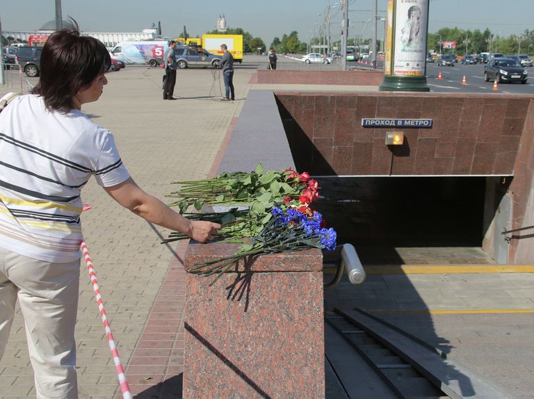 Женщина возлагает цветы у пешеходного перехода станции метро Парк победы Женщина возлагает цветы у пешеходного перехода станции метро Парк победы