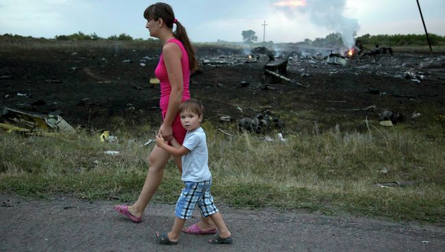 Женщина с ребенком проходят мимо места крушения крушения самолета Боинг 777 в Донецкой области Женщина с ребенком проходят мимо места крушения крушения самолета Боинг 777 в Донецкой области