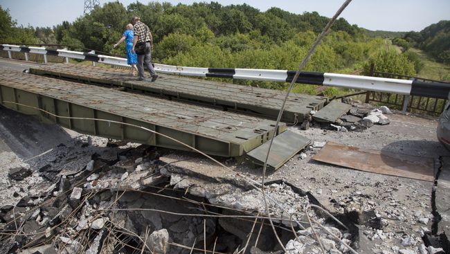 Люди идут мимо разрушенного моста в Донецкой области. Архивное фото