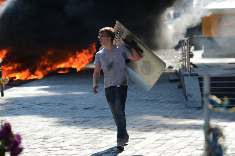 Активист идет мимо подожженных покрышек на площади Независимости в Киеве Активист идет мимо подожженных покрышек на площади Независимости в Киеве