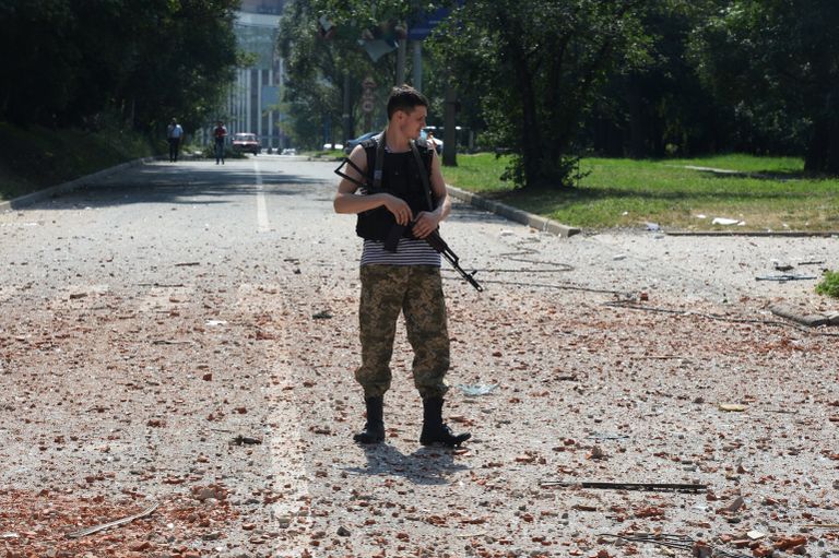 Ополченец около жилого дома в центре Донецка, пострадавшего при артиллерийском обстреле города украинской армией