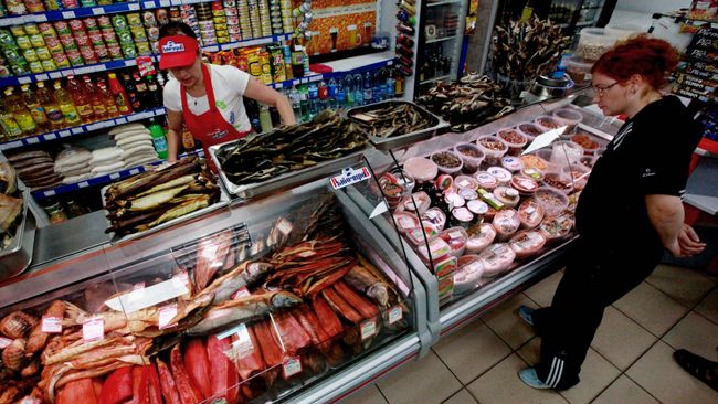 Женщина рассматривает рыбную продукцию в магазине. Архивное фото Женщина рассматривает рыбную продукцию в магазине. Архивное фото