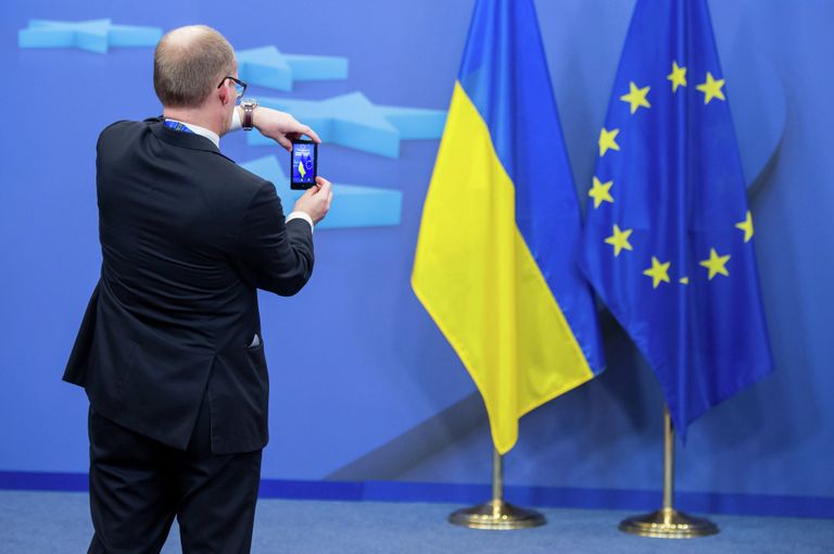 Человек фотографирует флаги Украины и Евросоюза Человек фотографирует флаги Украины и Евросоюза