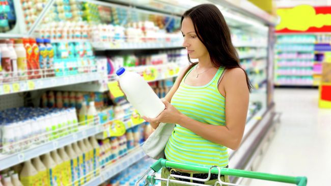 Женщина выбирает молочную продукцию в магазине